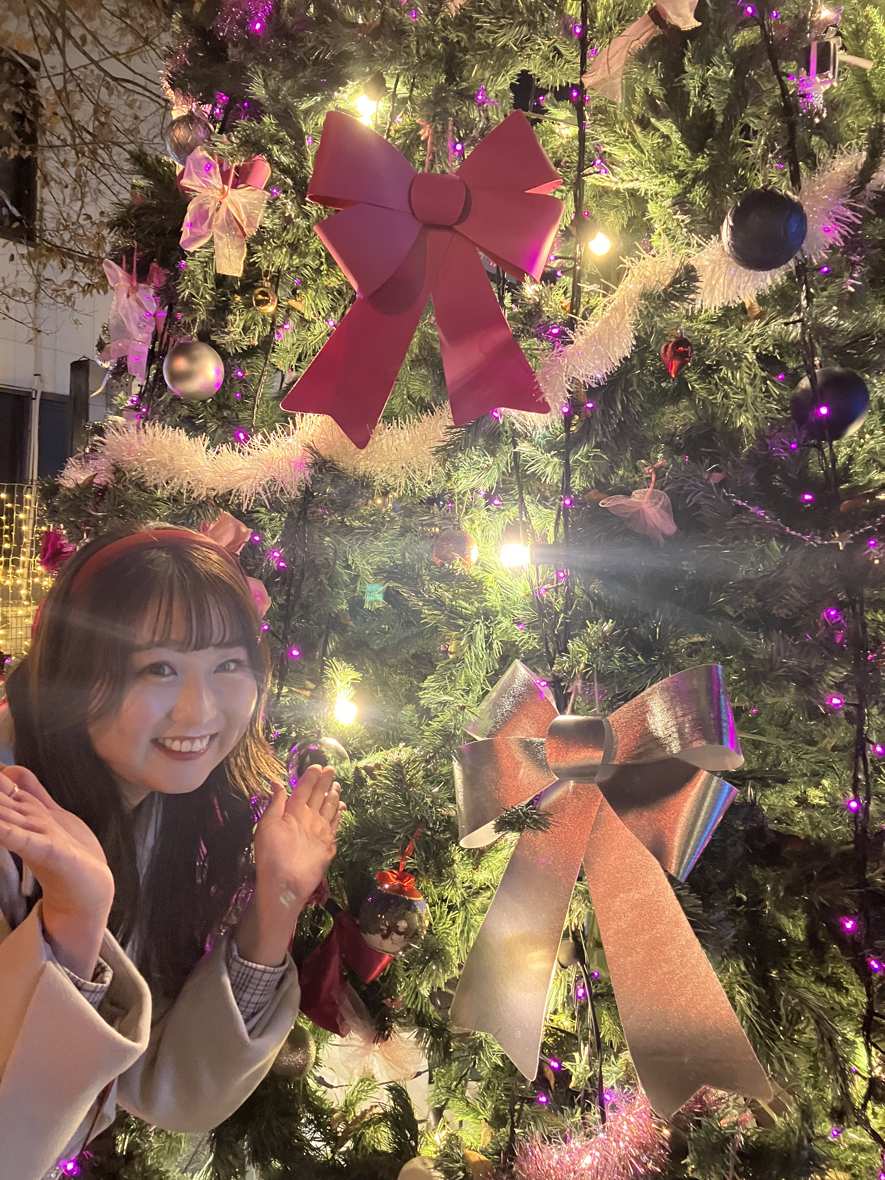 クリスマスツリーの前に立っている女の子低い精度で自動的に生成された説明